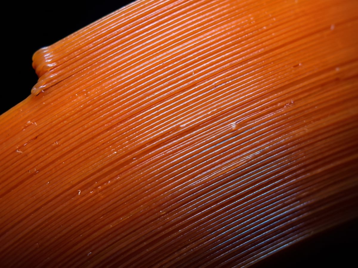 Macro das linhas de camada de uma peça impressa em 3D em PLA laranja